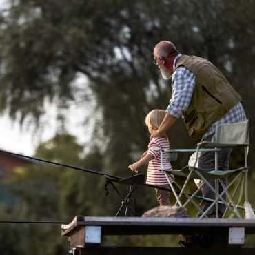 Grandfather and child fishing on dock