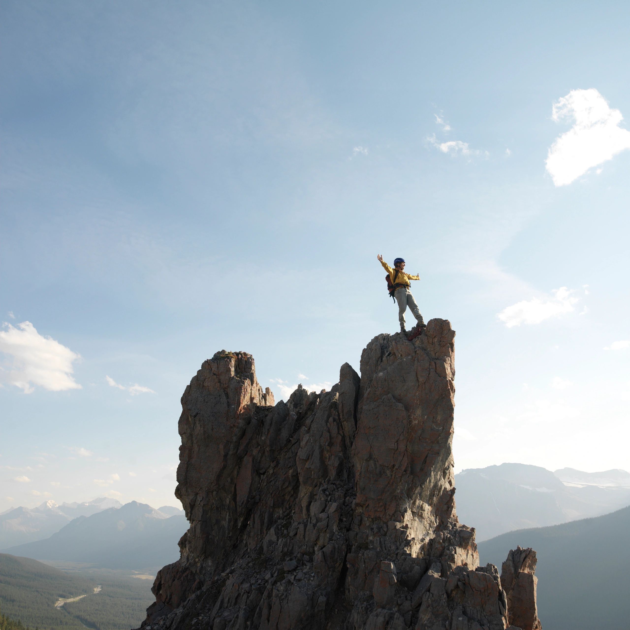 Person in yellow jacket on mountain rock